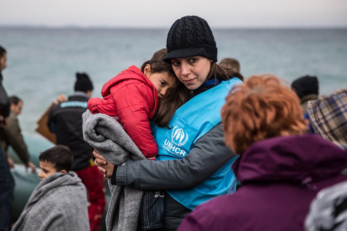 Refugee arrivals in Lesvos A UNHCR staff member holds a young refugee child in a blanket.